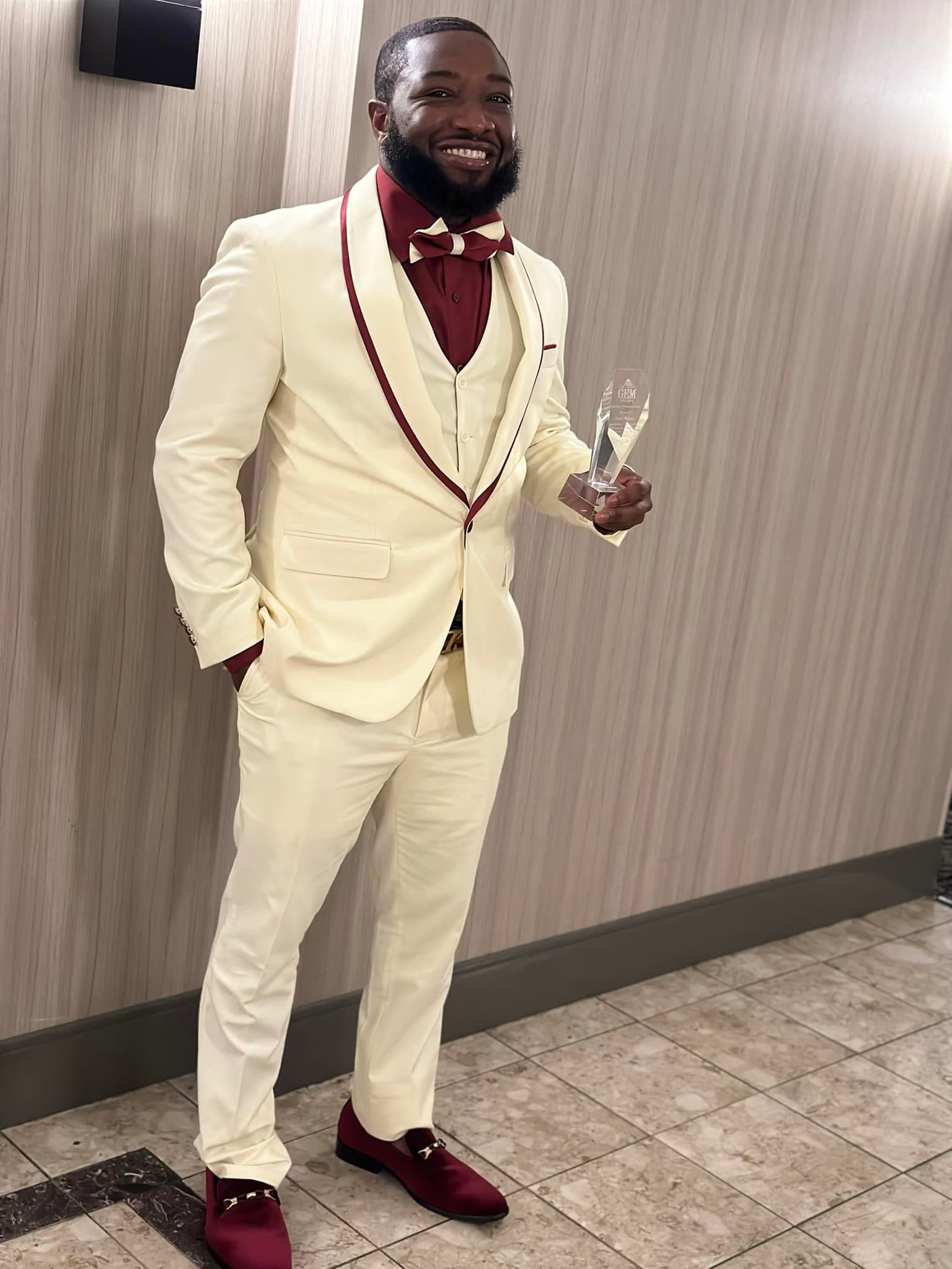 David Weaver in a cream suit holding an award
